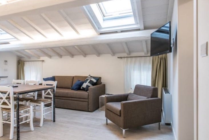 Dachwohnzimmer mit Sofa, Sessel, Esstisch und Dachfenstern